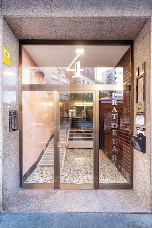 A modern building entrance with a glass door, a visible staircase, and a sign with the number '4'.