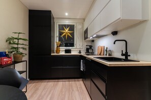 Une cuisine moderne avec des meubles de rangement noirs, un plan de travail en bois et un évier noir.