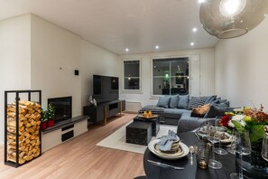 Ein modernes Wohnzimmer mit Sofa, Fernseher und Essbereich, der zum Essen eingerichtet ist.