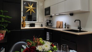 Een moderne keuken met zwarte kastjes, een wit aanrecht, een stersieradentje op het raam, een spoelbak en een koffiezetapparaat.