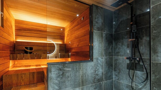 Een moderne badkamer met houten lambrisering, een douche met glazen wanden en een ingebouwde bank.
