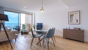 Un salon moderne avec un coin repas, de grandes fenêtres et une vue sur la mer.