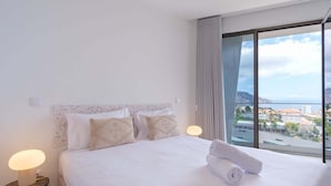 Une chambre d’hôtel avec un grand lit, une lampe de chevet et une vue sur la ville par une grande fenêtre.