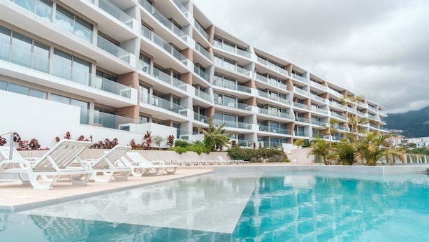 Un hôtel moderne doté d’une piscine, de nombreux balcons et offrant une vue sur les montagnes.