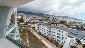 Un balcon offrant une vue sur le paysage urbain de la côte, avec ses bâtiments et ses montagnes.