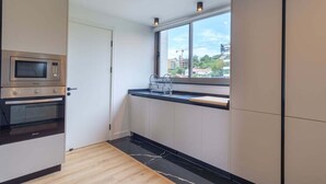 Une cuisine moderne équipée d’un four à micro-ondes, d’un four traditionnel et d’une fenêtre donnant sur des immeubles.