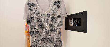 A garment with a V-neck and short sleeves, adorned with silver embellishments and buttons, hanging on a black hanger against a white wall.