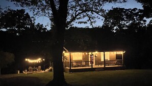 A house with a porch and outdoor seating area, surrounded by trees.