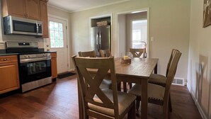 A kitchen with wooden cabinets, a microwave, an oven, and a dining table with chairs.