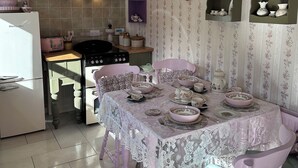 Une cuisine avec des placards roses, une cuisinière et une table à manger dressée avec de la vaisselle à motifs floraux.