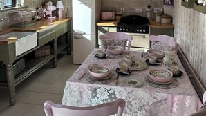 Une cuisine équipée d’une table à manger pour quatre personnes, d’un réfrigérateur, d’une cuisinière et de meubles de rangement roses.