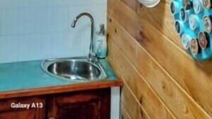 Een keuken met houten wanden, een plafondventilator en planken met keukengerei.
