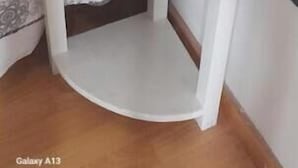 Een hoek van een kamer met een bed, nachtkastje en een spiegel.