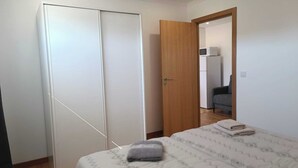 A bedroom with a bed, a wardrobe, and a door leading to another room. - Mondalva Apartments located in village of Quintela, near to São Pedro de Alva (São Pedro de Alva)