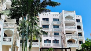 Un hôtel à plusieurs étages doté de balcons, d’une cour intérieure et de palmiers.