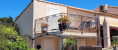 Un bâtiment à deux étages doté d’un balcon orné d’une balustrade en fer forgé et de plantes en pot.