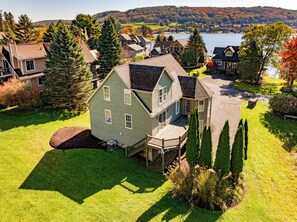 A two-story house with a front deck and a large yard.