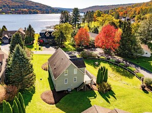 A residential area with a house surrounded by a well-maintained lawn, a dock by the water, and autumn-colored trees. - Ski Boots N' Bathing Suits by Taylor Made Deep Creek (McHenry)
