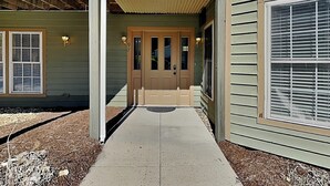 A two-story building with a covered entryway, a front door, and a visible mailbox. - Ski Boots N' Bathing Suits by Taylor Made Deep Creek (McHenry)