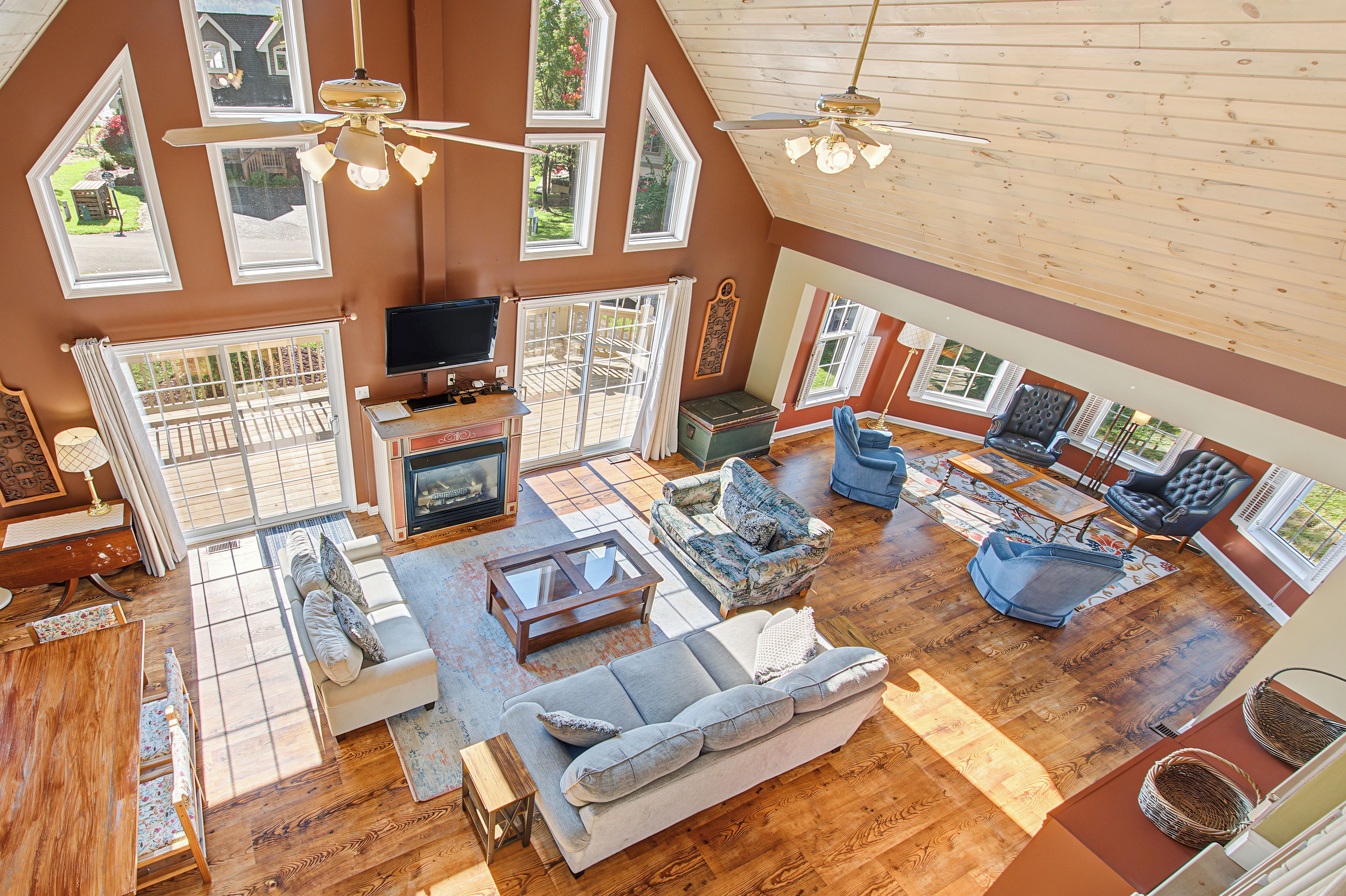 A spacious living room with a fireplace, multiple seating areas, and large windows offering views of the outdoors.
