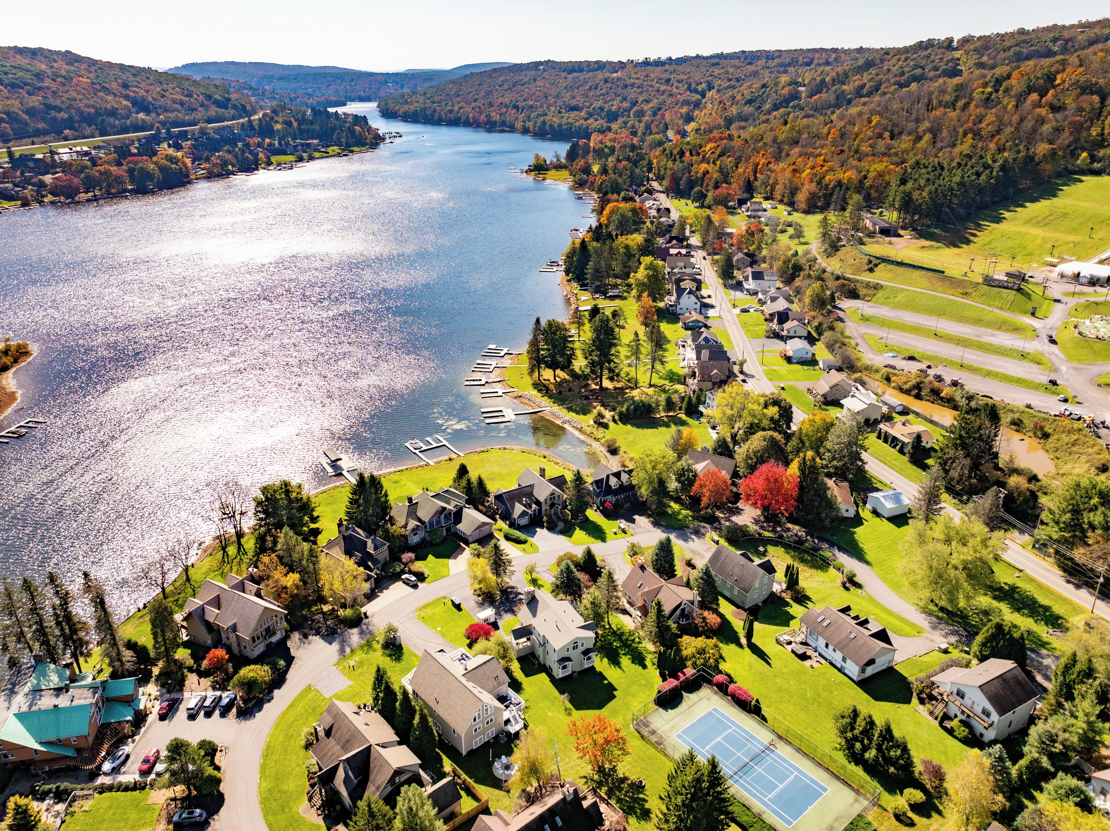 A residential area with houses, a tennis court, and a river.