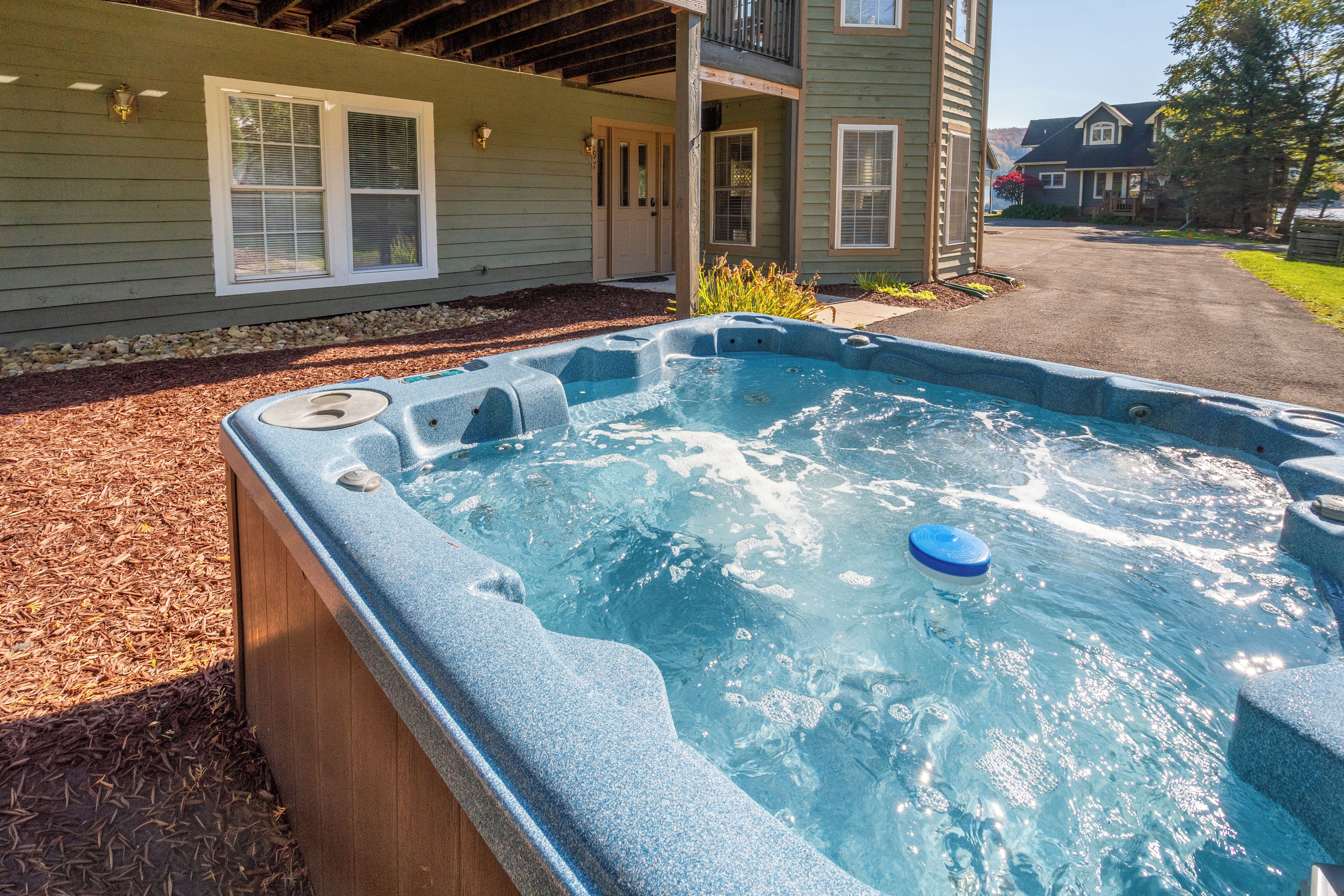 Ein Whirlpool auf einer Holzterrasse mit einem Haus im Hintergrund.