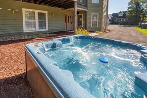 A hot tub in a wooden deck area with a house in the background. - Ski Boots N' Bathing Suits by Taylor Made Deep Creek (McHenry)