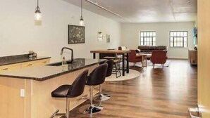 Una cocina moderna con una isla central, taburetes de bar y un comedor con mesa y sillas.
