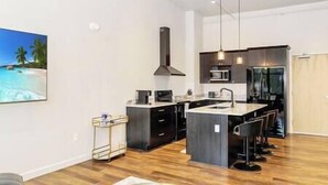 A modern kitchen with a central island, black cabinetry, and stainless steel appliances.