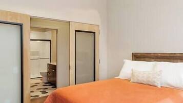 A bedroom with a bed, a wardrobe, and a mirror.