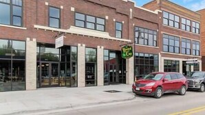 A two-story building with a brick facade, large windows, and a sign for 'The Beard Cap'.