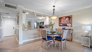A spacious kitchen with a central island, a dining area with blue chairs, and a large painting on the wall. - Sweet EmOCEAN at Jupiter Bay. (Jupiter)