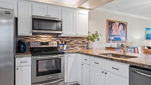 A modern kitchen with white cabinets, stainless steel appliances, and a tiled backsplash. - Sweet EmOCEAN at Jupiter Bay. (Jupiter)
