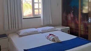 A hotel room with a bed, a window with curtains, an air conditioning unit, a nightstand, and a wardrobe with a tropical mural. - Pousada e Restaurante Mar dos Sonhos (Paripueira)