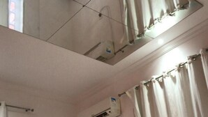A hotel room with a bed, an air conditioning unit, a window with curtains, and a towel on the bed. - Pousada e Restaurante Mar dos Sonhos (Paripueira)