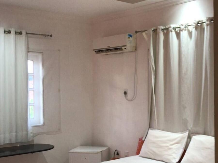 Quarto de hotel com cama, mesa de cabeceira, espelho e ar condicionado.