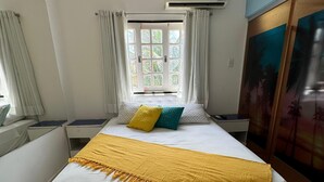 A bedroom with a bed, white curtains, a window with a view of palm trees, and an air conditioning unit. - Pousada e Restaurante Mar dos Sonhos (Paripueira)