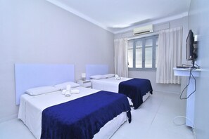 A hotel room with two beds, a TV, and a window with curtains.