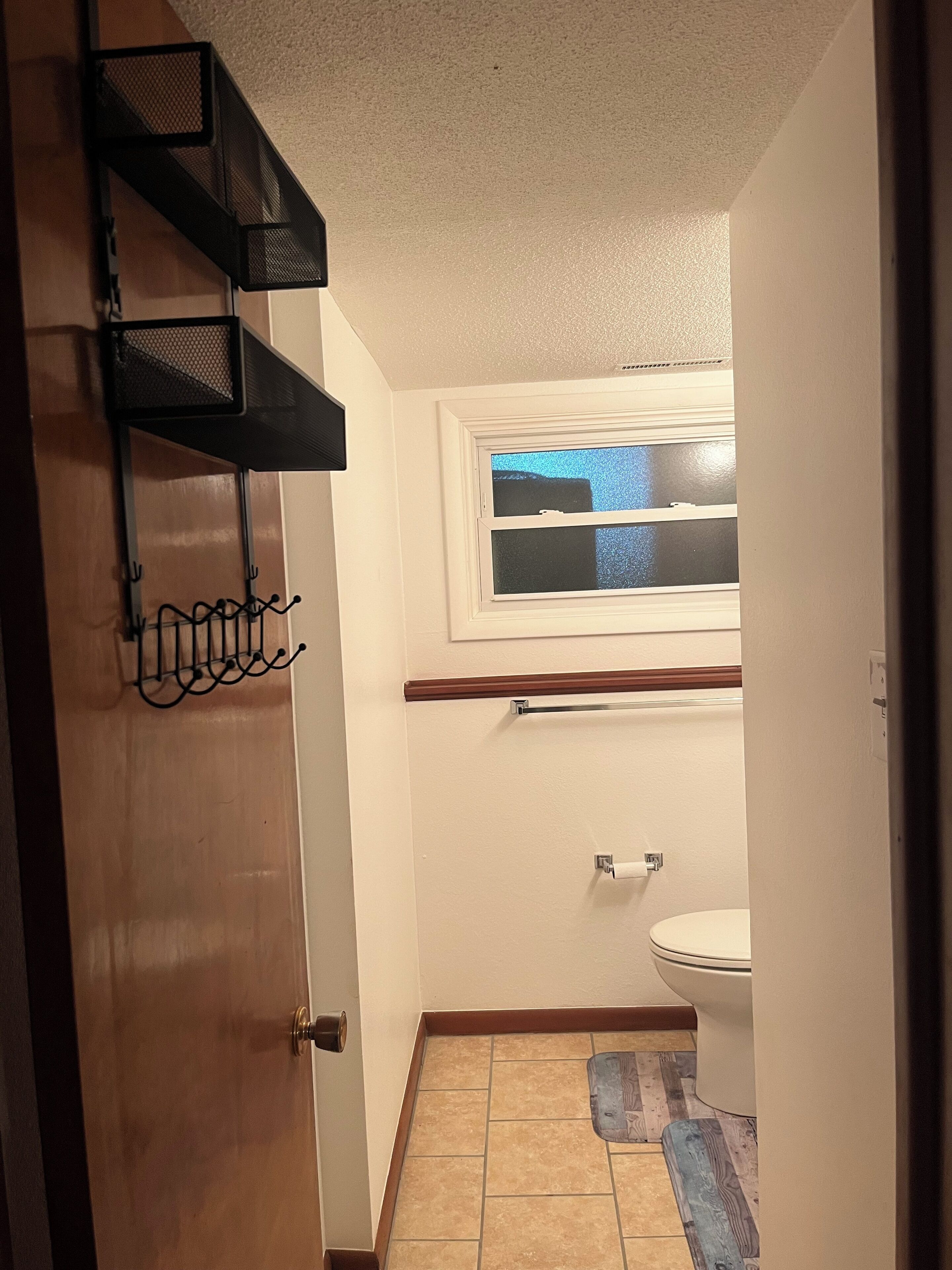 Une petite salle de bain avec des toilettes, une fenêtre et un porte-serviettes.