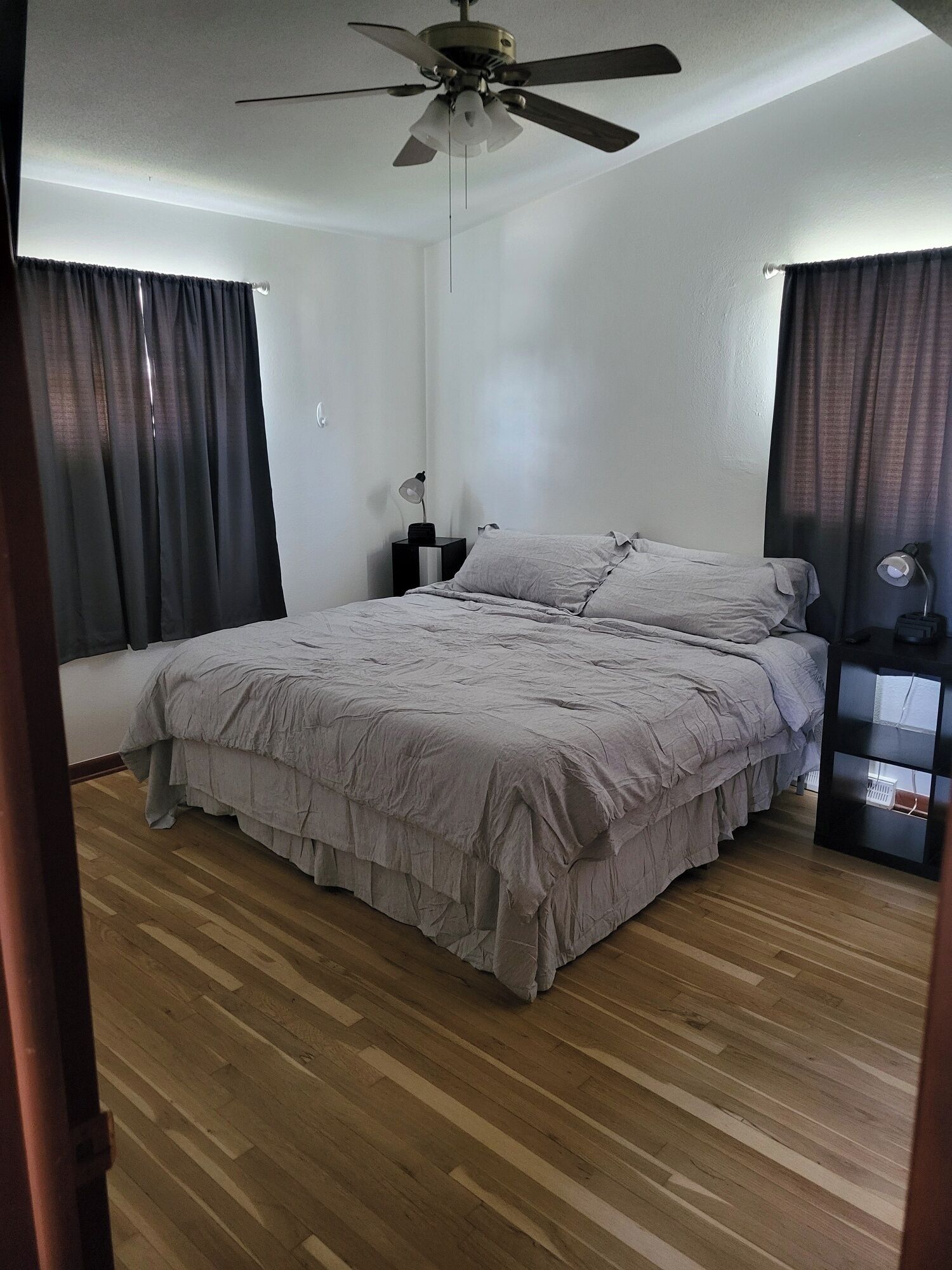 A bedroom with a bed, a ceiling fan, a nightstand, and a lamp.