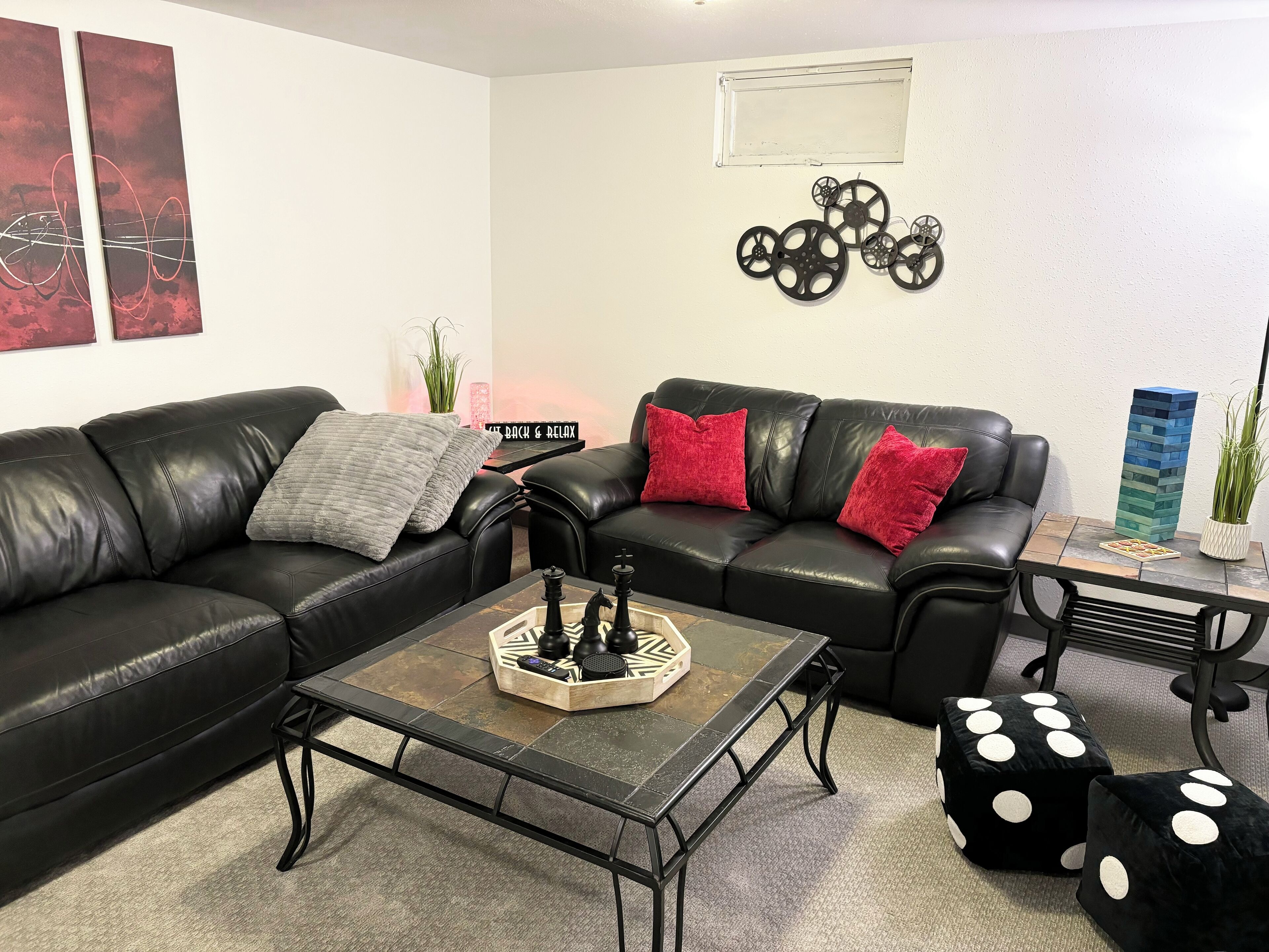 A living room with a black leather sofa, a coffee table with chess pieces, and dice on the floor.