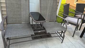 A patio with two wicker chairs and a small table.