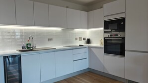 Una cocina moderna con armarios blancos, un lavamanos de acero inoxidable y un horno Bosch.