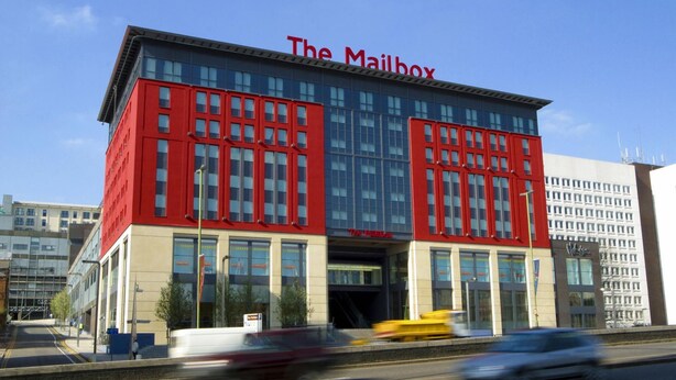 Un edificio moderno con fachada roja y ventanas amplias, con la leyenda 'The Mailbox'.