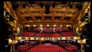 Un auditorio amplio y de varios niveles con asientos rojos y un techo alto.