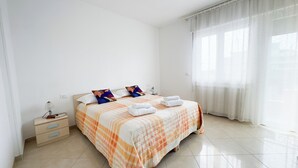 A hotel room with a bed, a nightstand, a lamp, and a window with curtains. - Esperia Apartment by Ca-Sa Check (Chioggia)