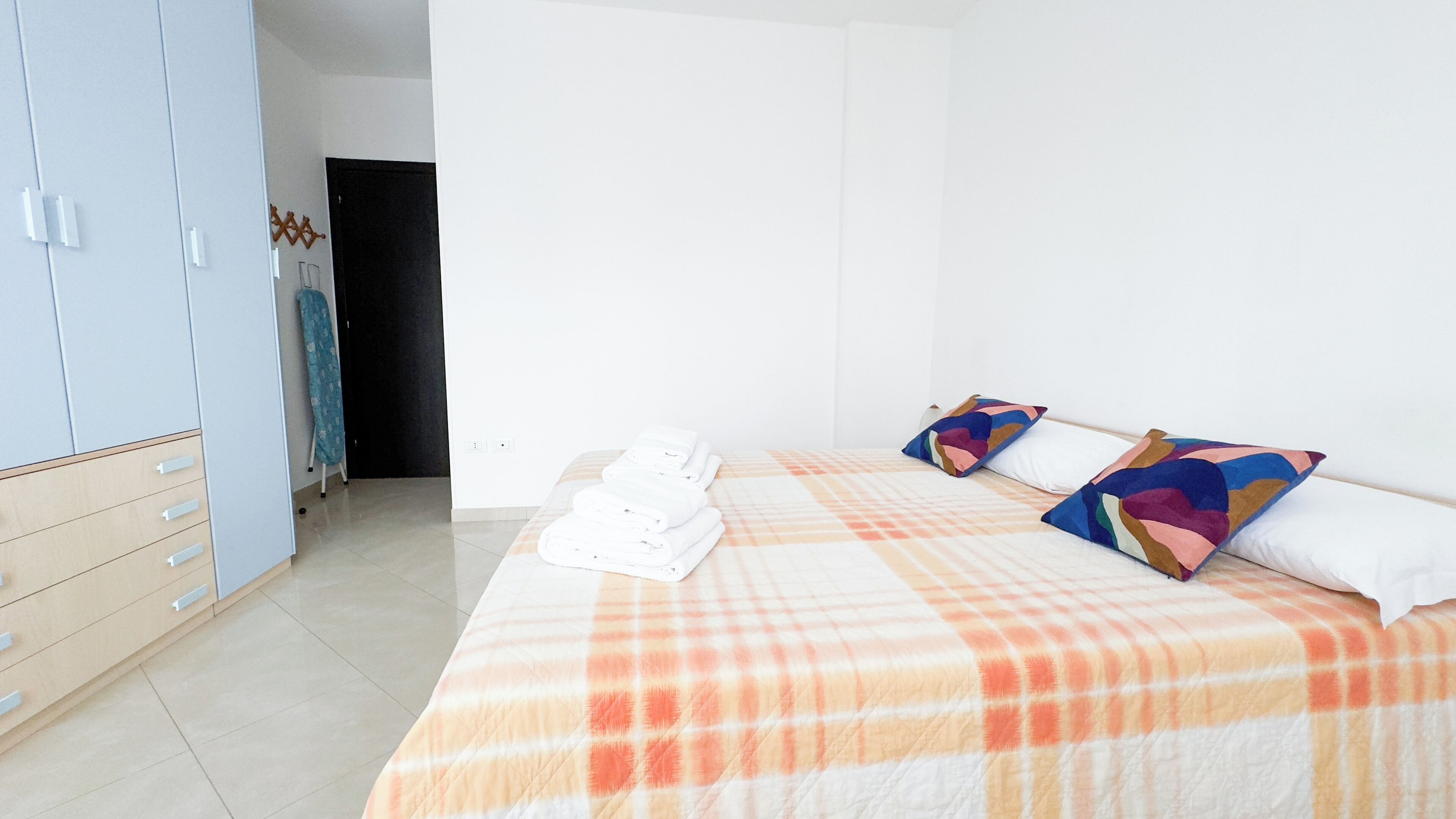 A hotel room with a bed, a wardrobe, and a door.