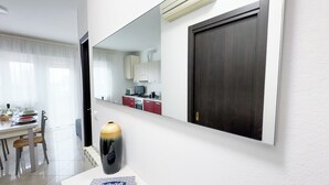 A modern kitchen with white cabinets, a stove, and a microwave. - Esperia Apartment by Ca-Sa Check (Chioggia)