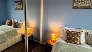 Hotellihuone, jossa on sänky, yöpöytä, peili ja seinä, jossa on koristeellinen taideteos.