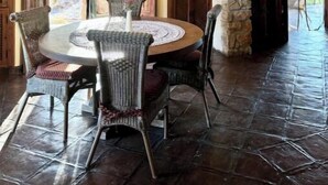 A dining area with a round table, chairs, and a stone archway.
